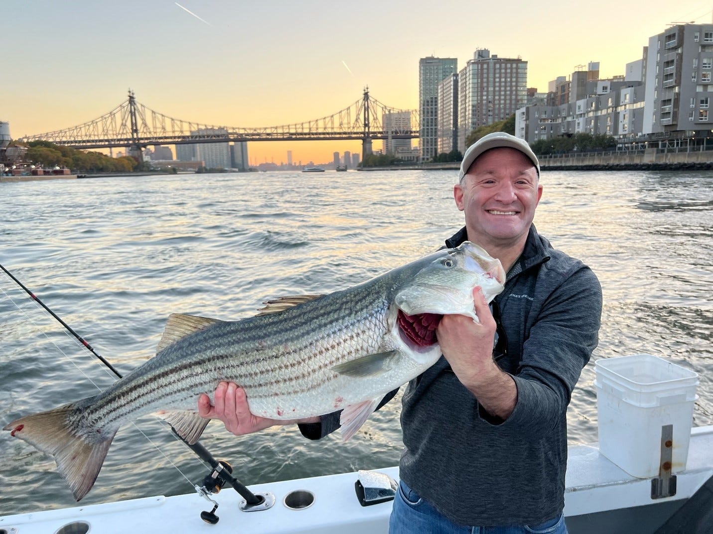 A person holding a fish in front of a body of water

Description automatically generated