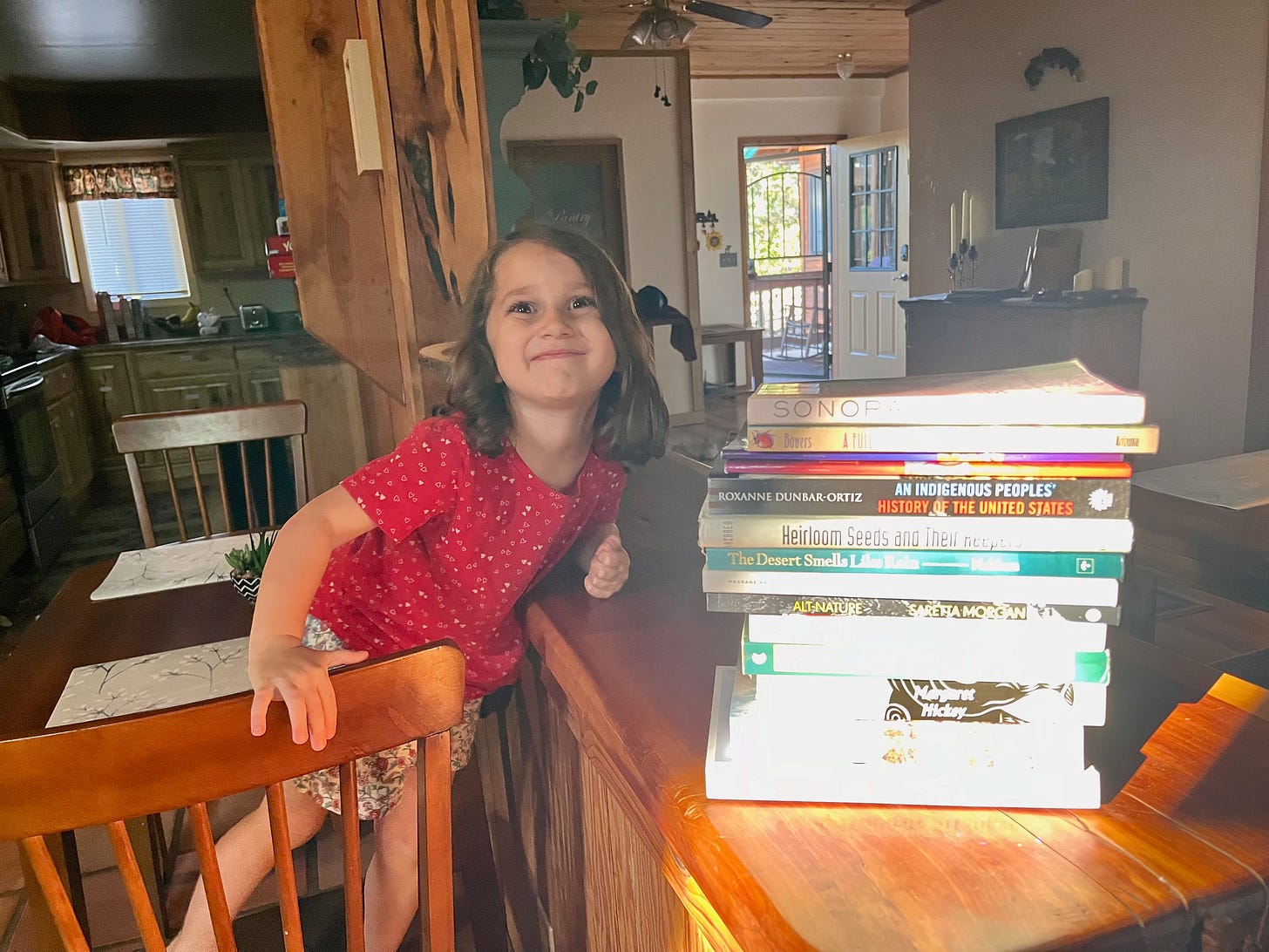 My four year old posing for a picture with my stack of books