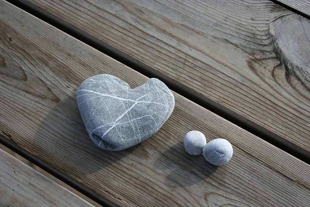 Stone shaped like a heart lying on a wooden deck