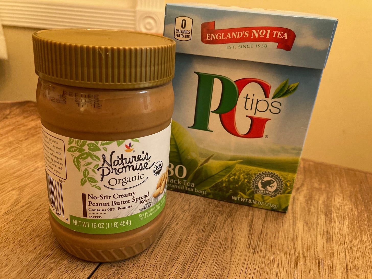 A jar of peanut butter and a box of tea on a wooden table
