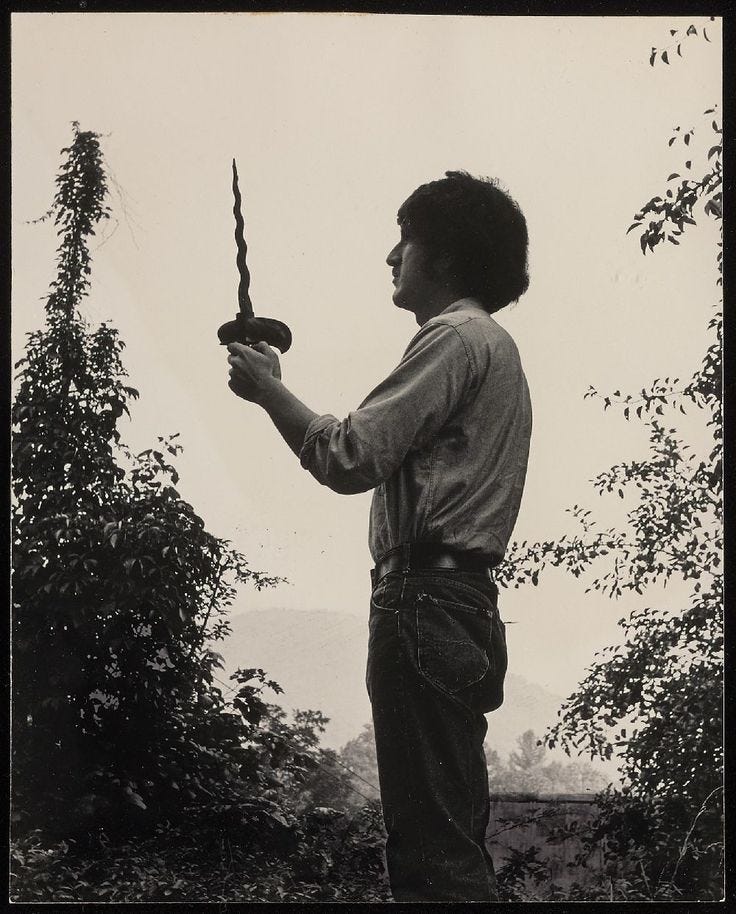 This may contain: an old photo of a boy holding a knife in one hand and looking at the other