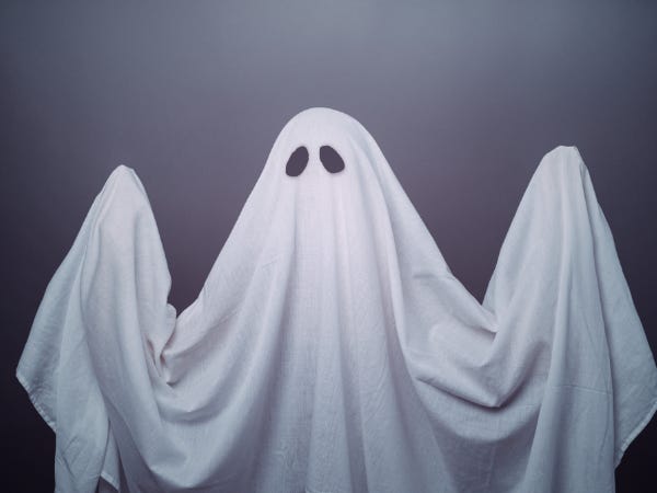 A person beneath a white sheet impersonating a ghost