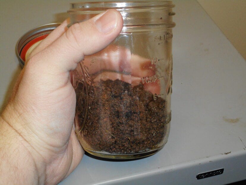 A jar filled a ⅓ of the way with soil.