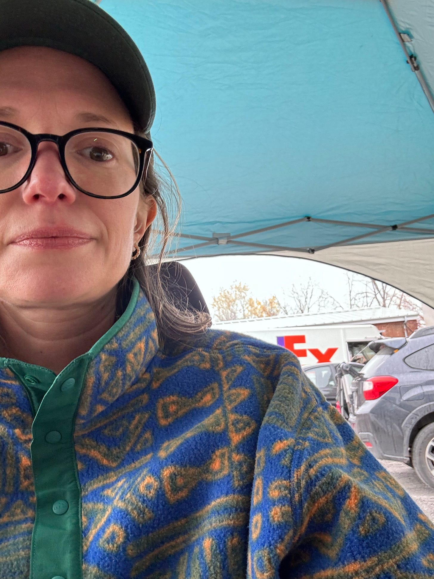 Jessica, in a 90s fleece, sits in her wheelchair under a tent