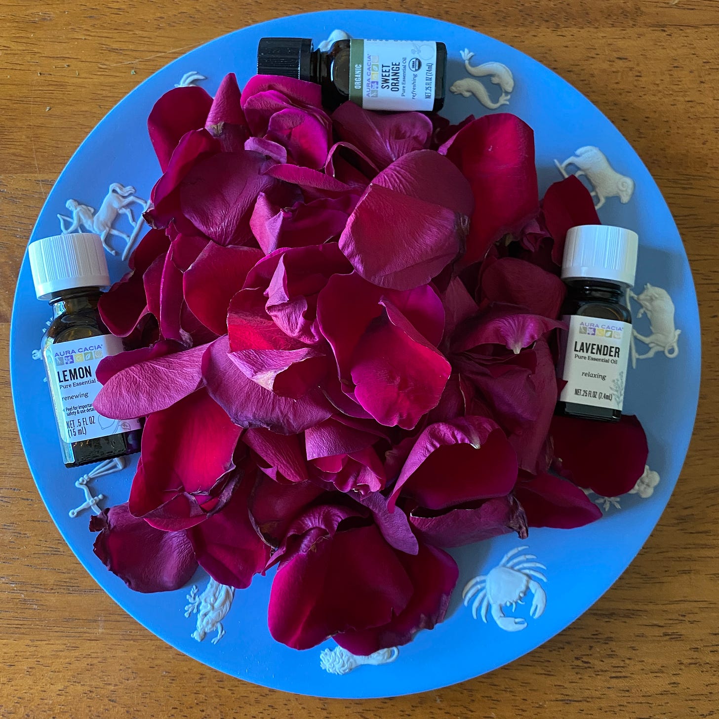 A plate covered in rose petals, surrounded by bottles of essential oils