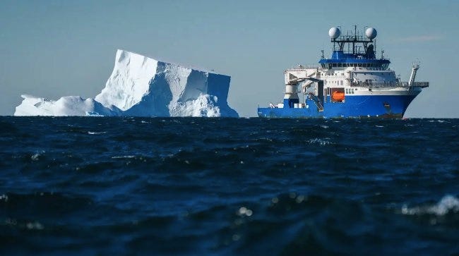 Un navire de rehcerche vogue auprès d'un iceberg en Antarctique