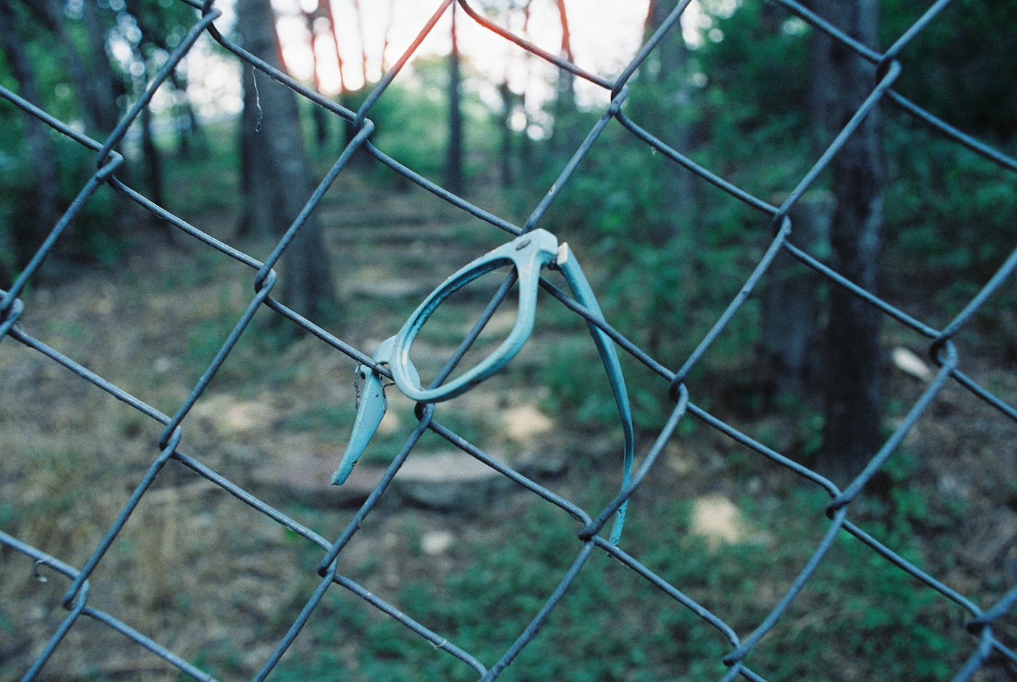 Broken blue Wayfarer-style sunglasses in chainlink fence