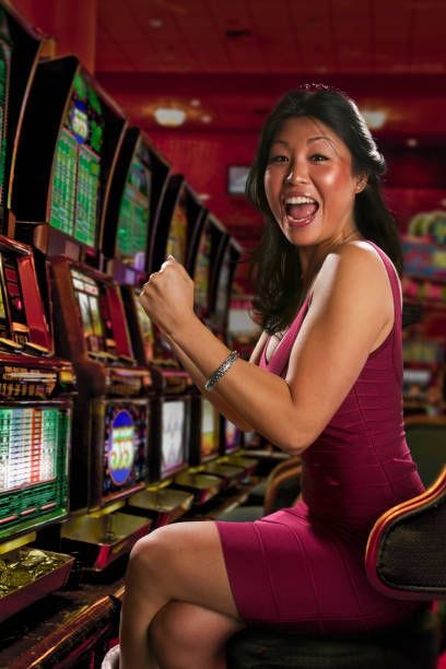 chinese woman playing slot machines in casino - slot machine stock pictures, royalty-free photos & images