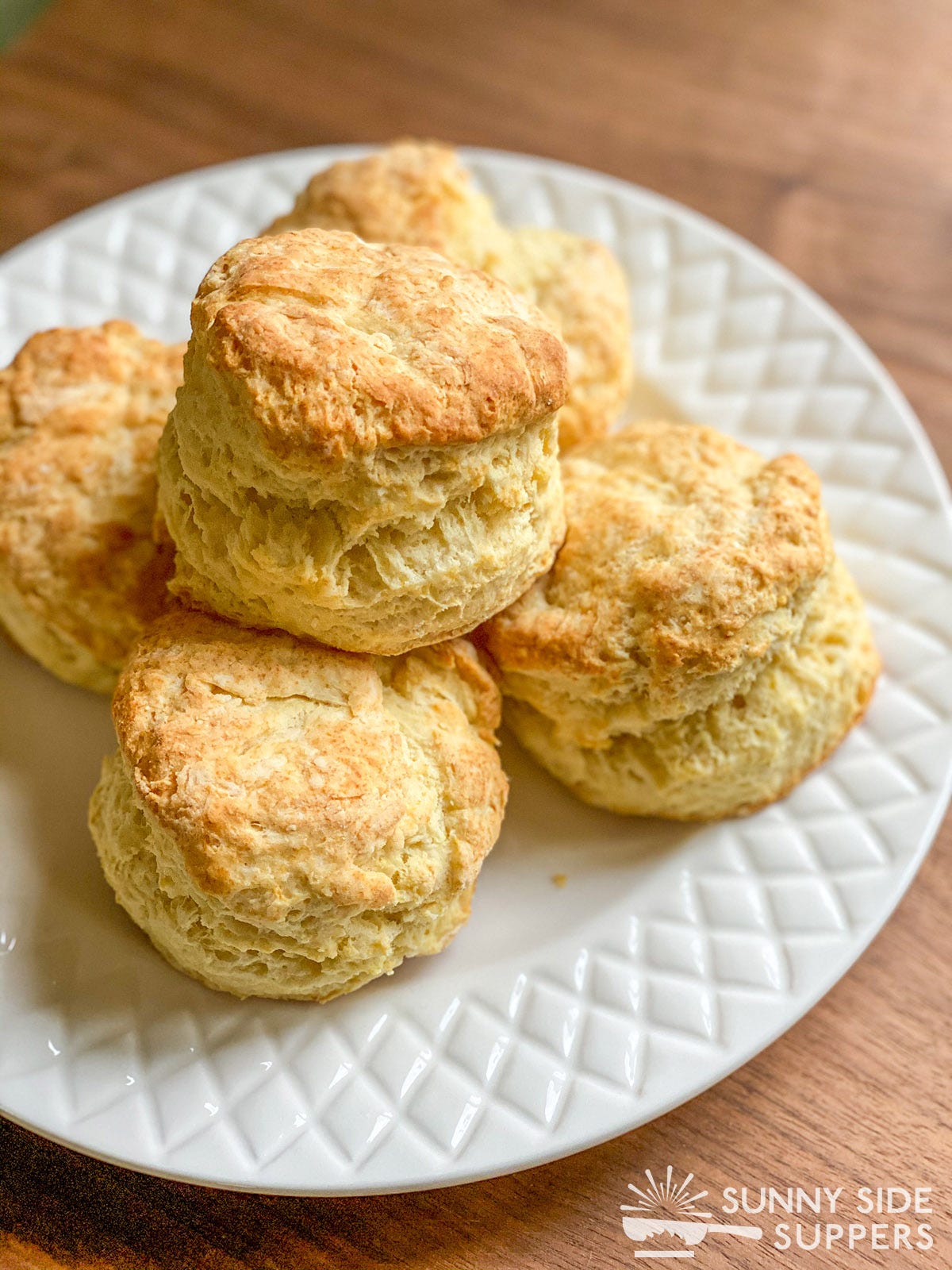 Golden buttermilk biscuits on a white plate.