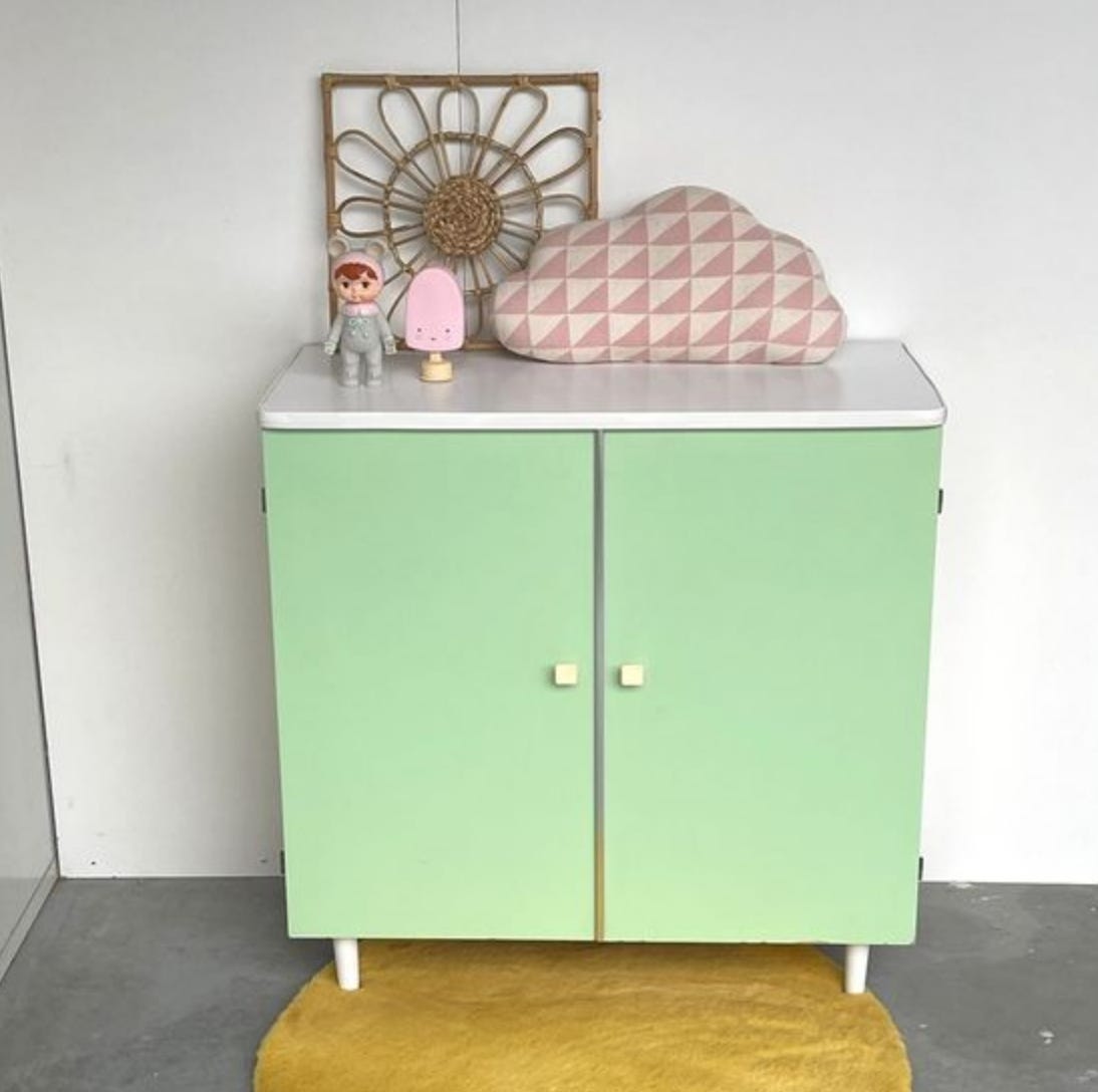 A retro sideboard with a white formica surface and legs. The doors are a minty green.