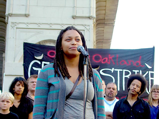 Crystallee at the mic at an Occupy Oakland event (filmmaker Boots Riley looks on)