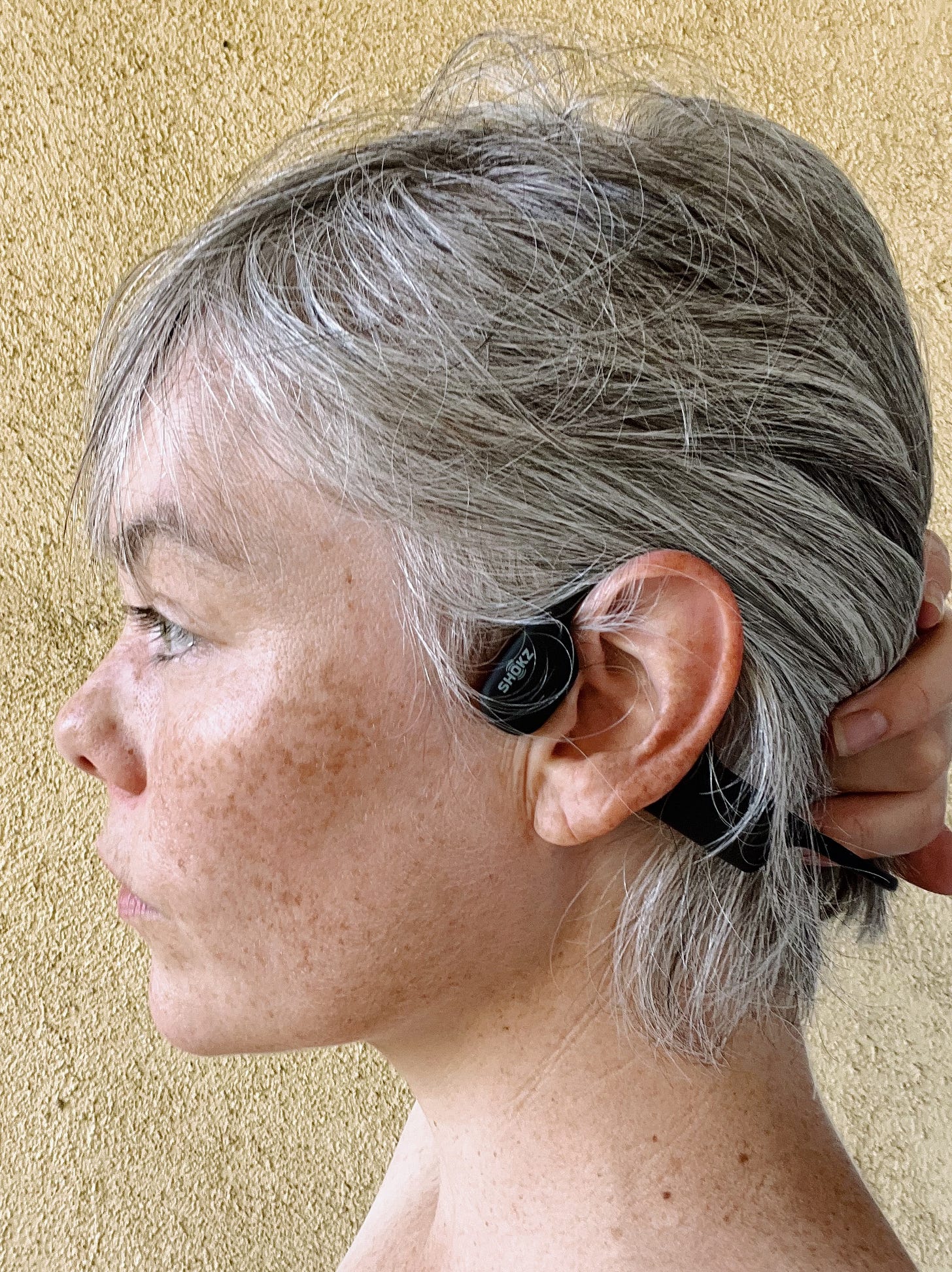 A photo of the author in profile showing the bone-conducting headphones she runs in.