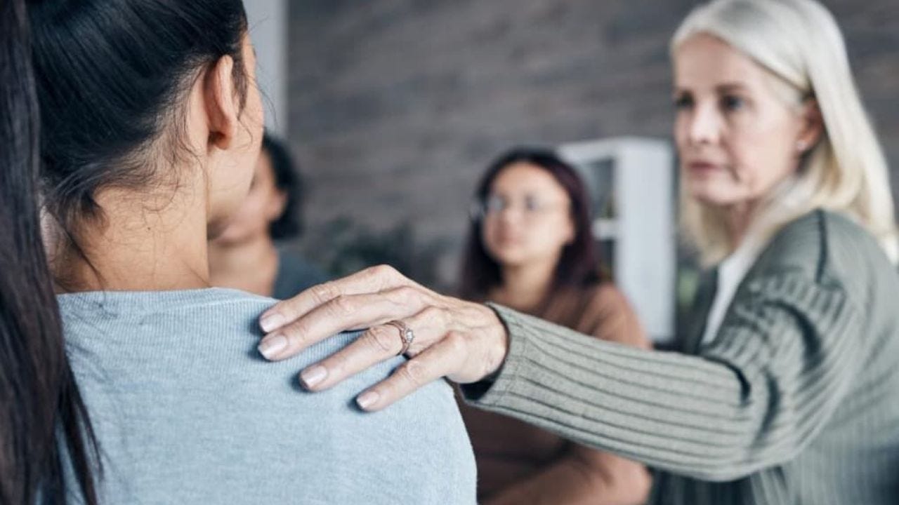 woman touching shoulder of another woman