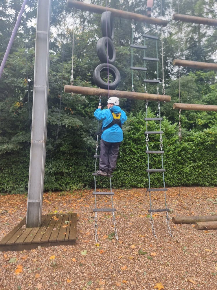 Me, in full waterproofs because it's pouring with rain, on the rope ladder that leads to the first beam of the multiscramble obstacle. I did not get any higher.