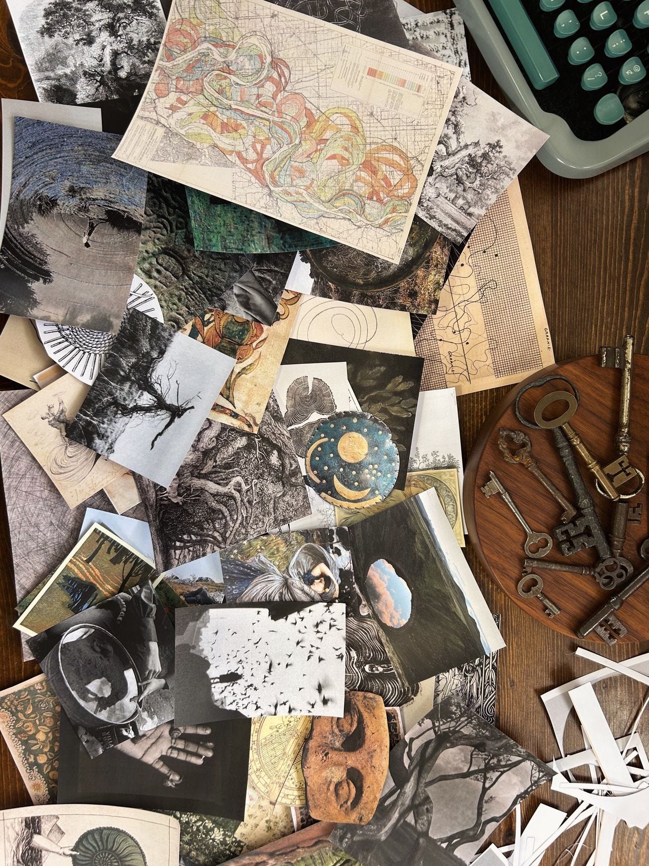 Printed images in a pile on my desk including maps, trees, spirals, artifacts, hag stones, reflections, etc. My typewriter and antique keys are also on the table.