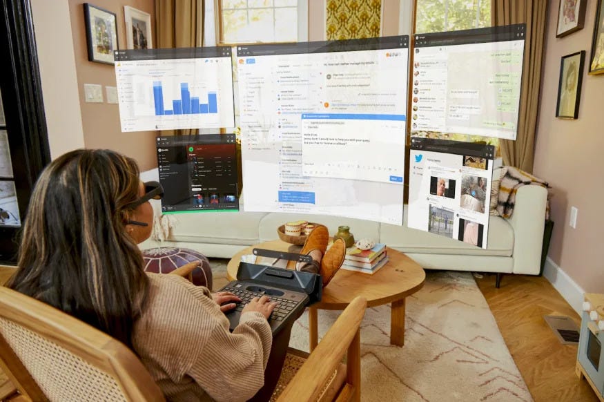 A woman uses Spacetop in her living room, which displays virtual computer desktop windows on a curved space in front of here via Augmented Reality (AR) glasses.