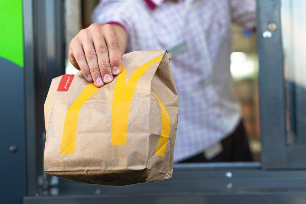 McDonald's employee handing a bag of fast food through the window at a drive thru service in Sankt-Petersburg, Russia