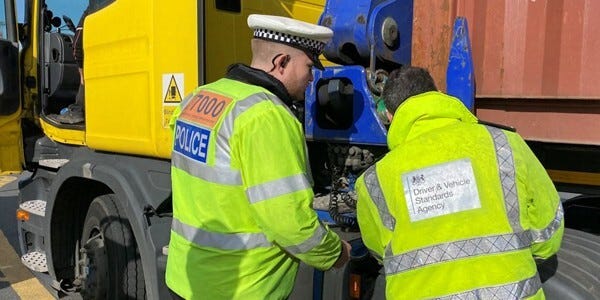 Police officer and Driver anf Vehicle Standards Agency Officer inspecting an HGV.