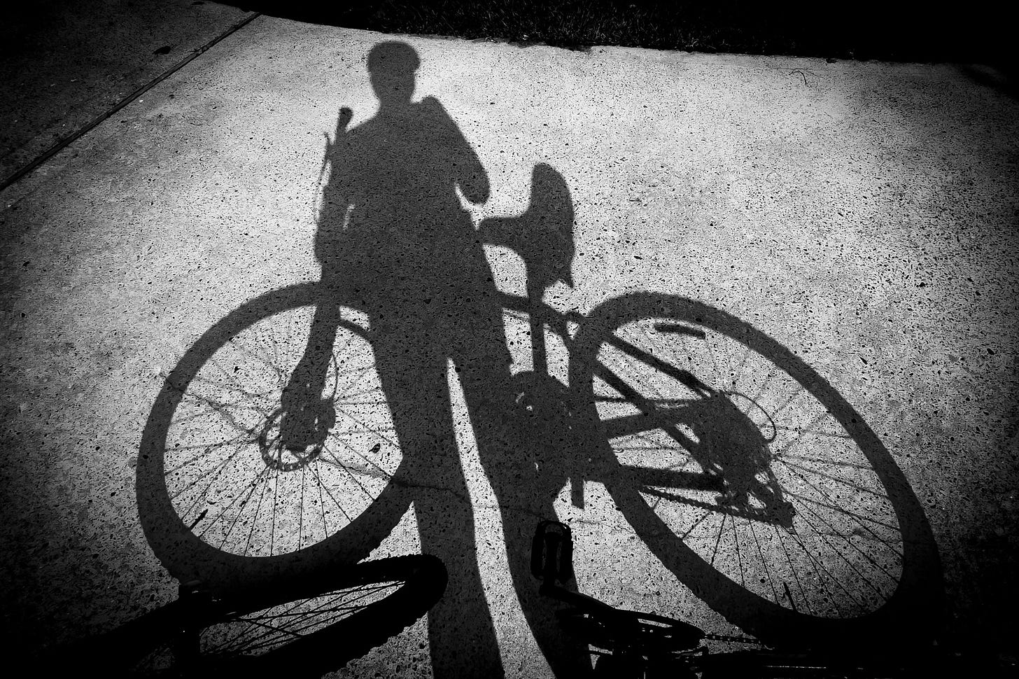 A black and white photo of the shadow of a bike and rider 