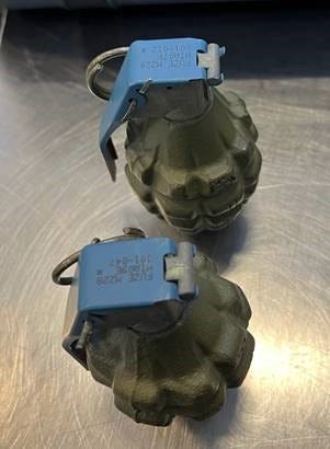 Two hand grenades sit on a stainless steel table.