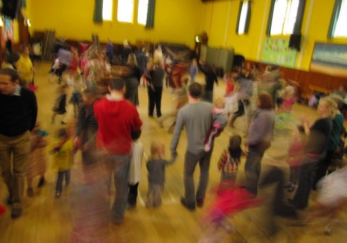 blurry photo of a family ceilidh dance with lots of small children dancing