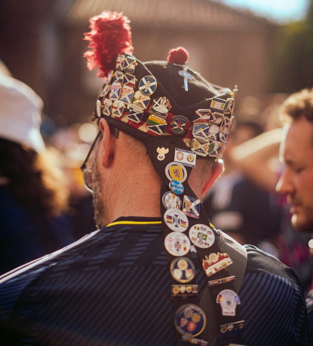 A man wearing a hat with a lot of buttons on it