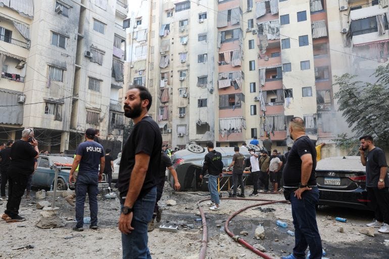 People inspect the site of an Israeli strike in the southern suburbs of Beirut