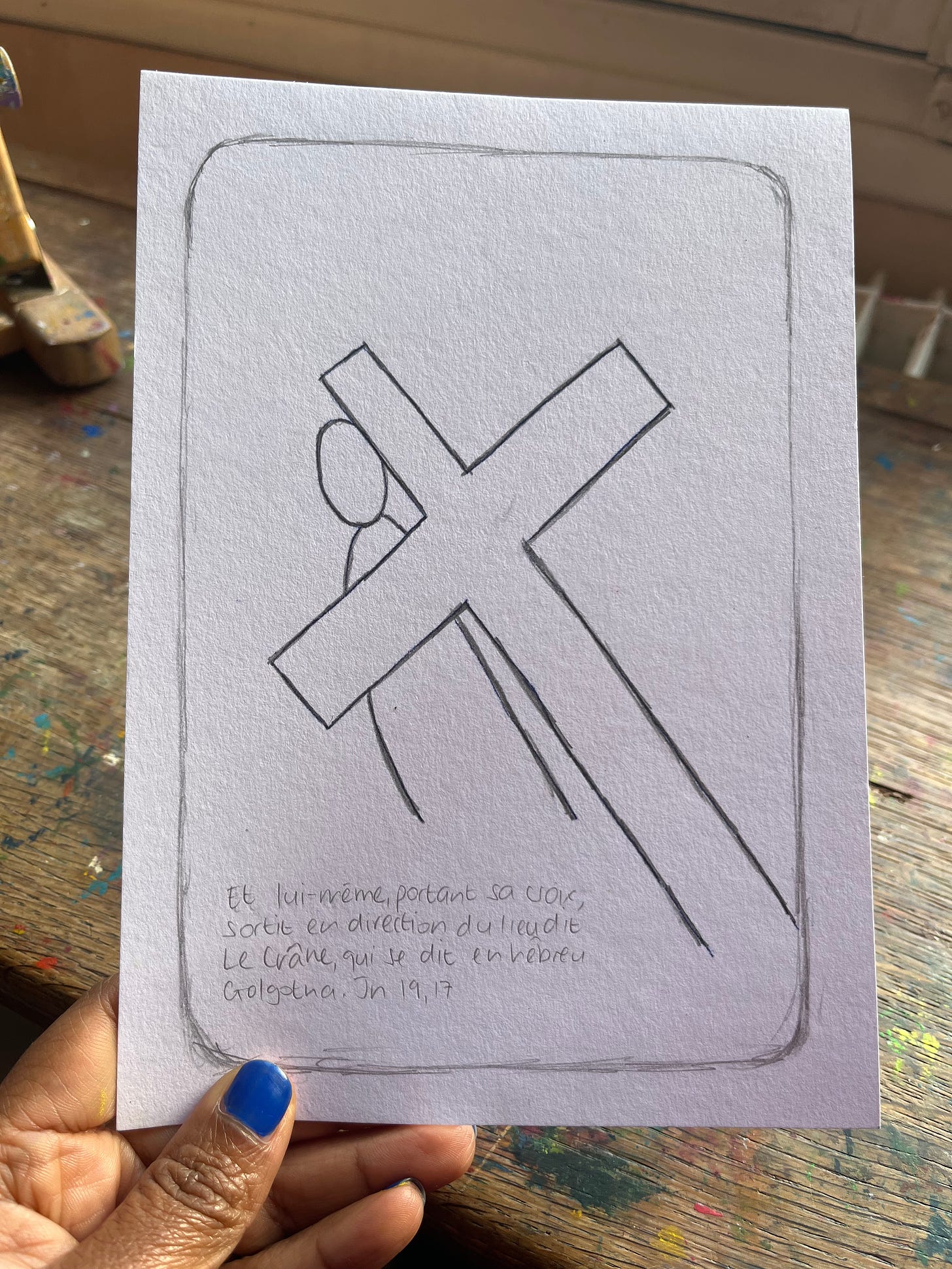 A black hand holding a drawing of a station of the cross