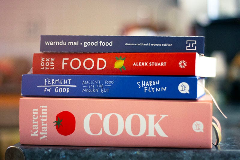 A stack of cookbooks - ‘Warndu Mai Good Food’ by Damien Coulthard and Rebecca Sullivan, ‘Low Tox Life Food’, by Alexx Stuart, ‘Ferment for Good’ by Sharon Flynn and ‘Cook’ by Karen Martini.