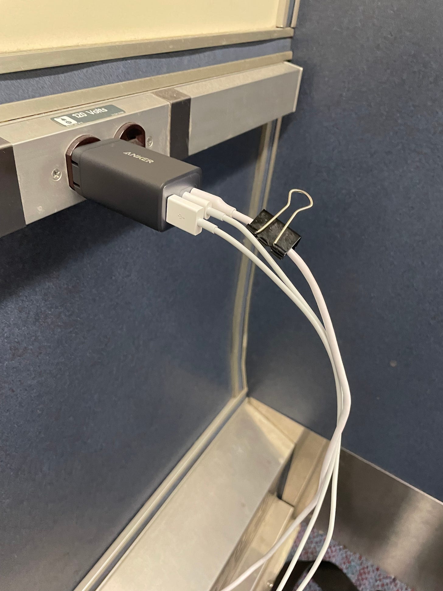 Phone charger plugged into an outlet next to a train seat.