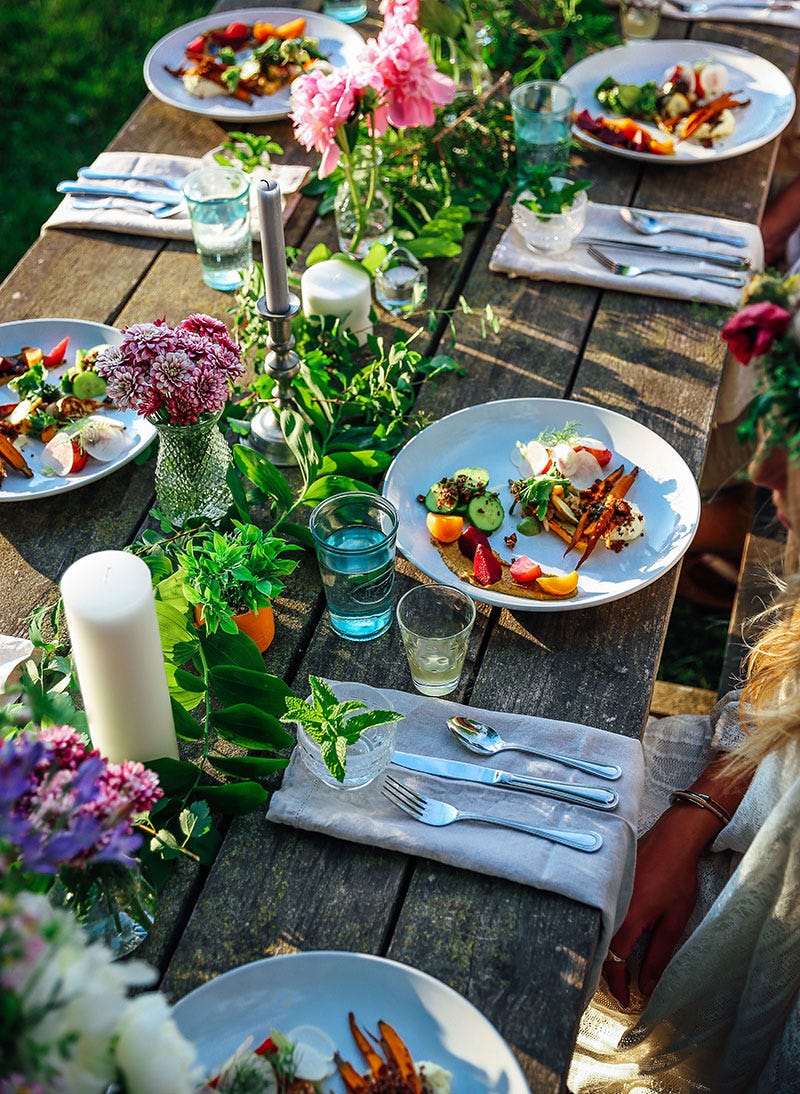 A table set with farm fresh plates of food and fresh flowers decorating the area.