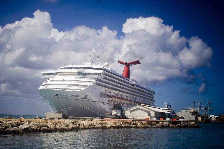 Photo of a large cruise ship looming over a small wharf.