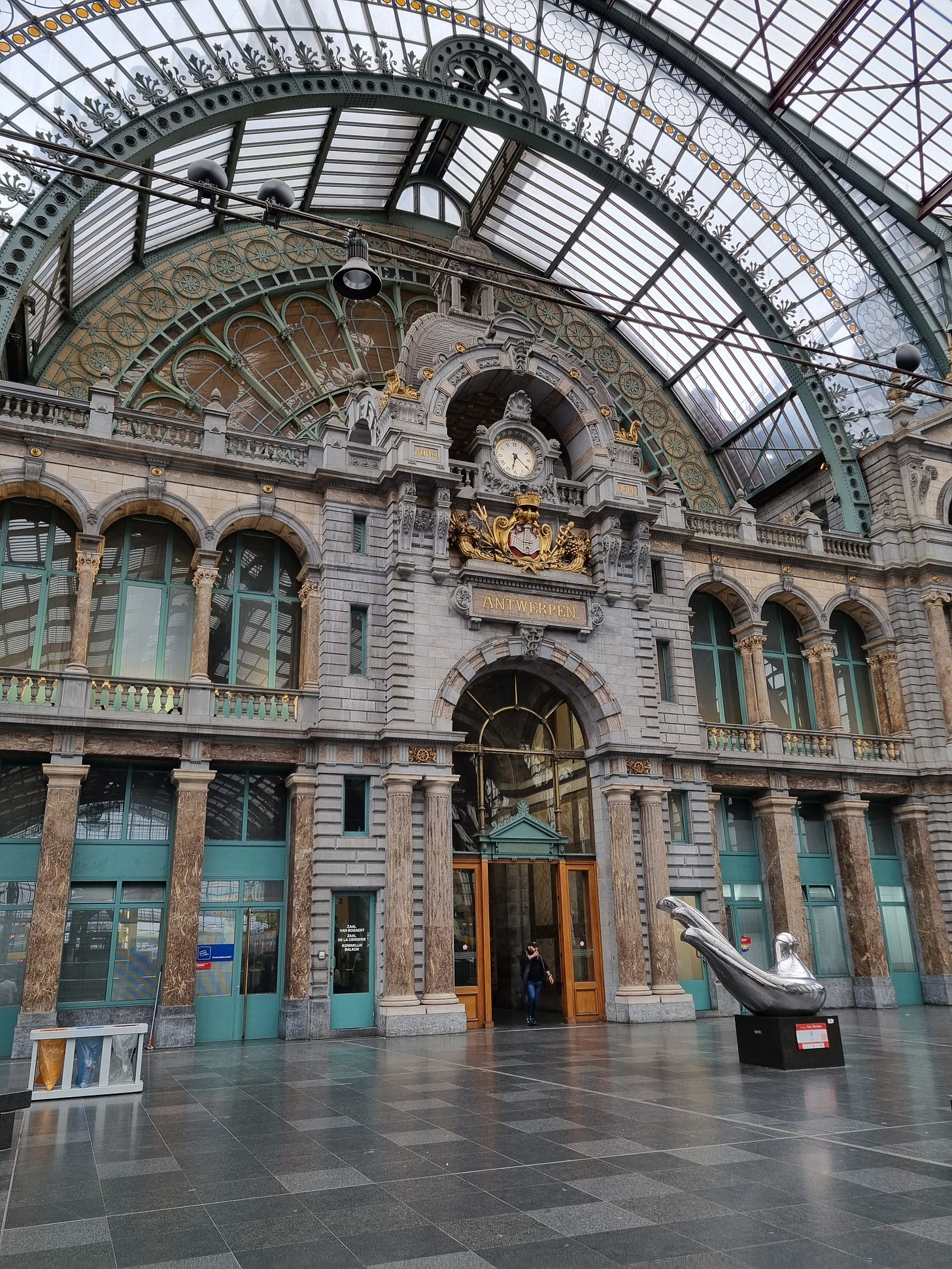 Photo of Antwerp station showing ornate metal work, glass, and scuplture.