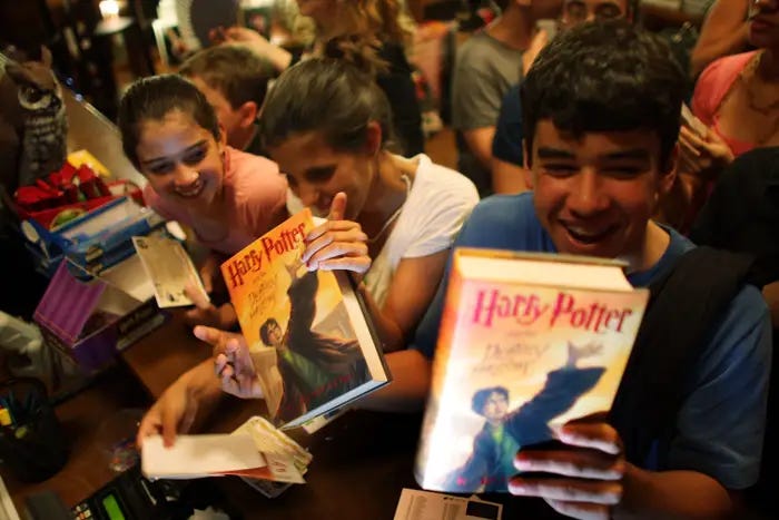 Adolescentes com o livro Harry Potter nas maos.