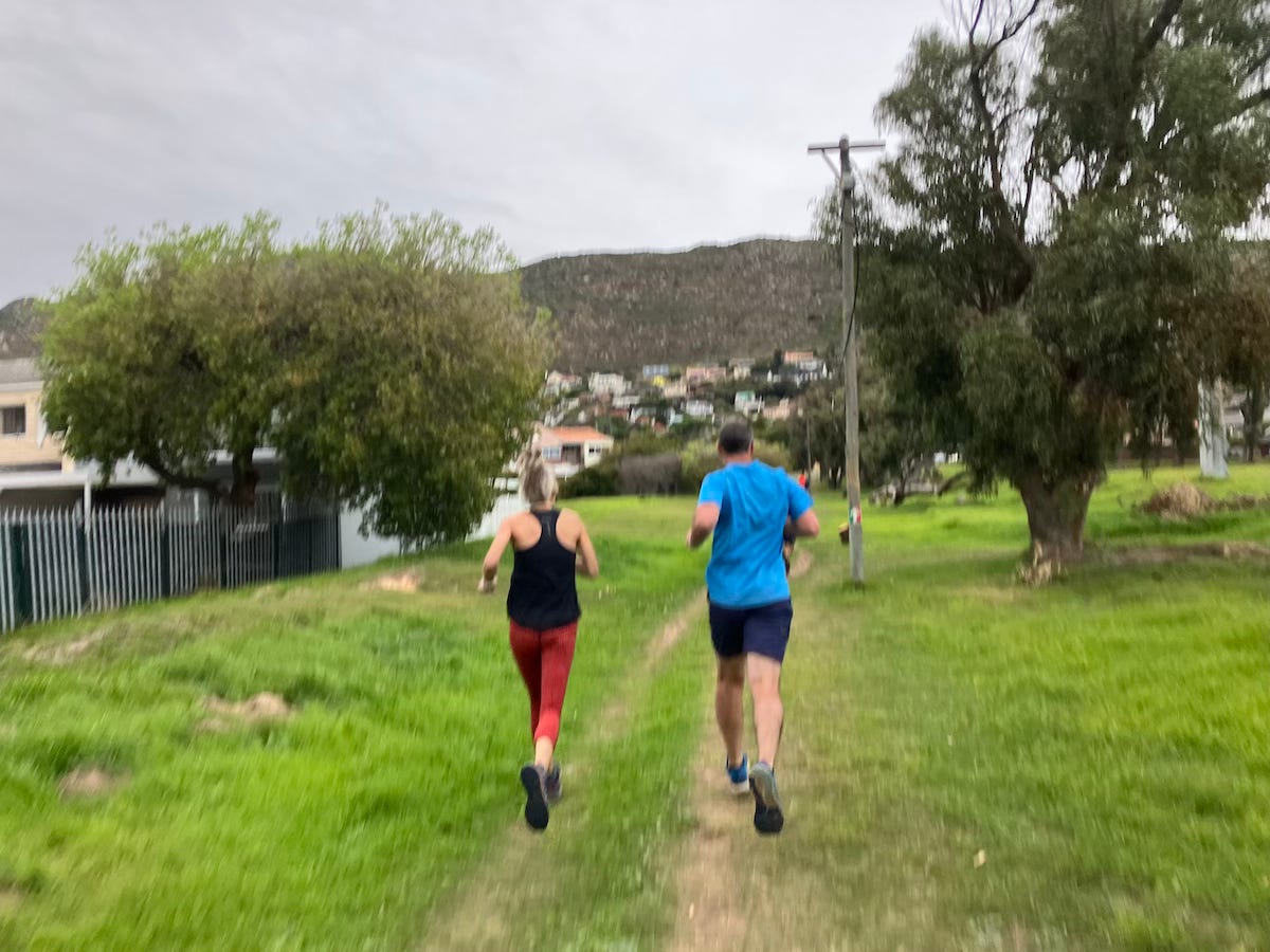 Runners side-by-side through worn tracks on grass