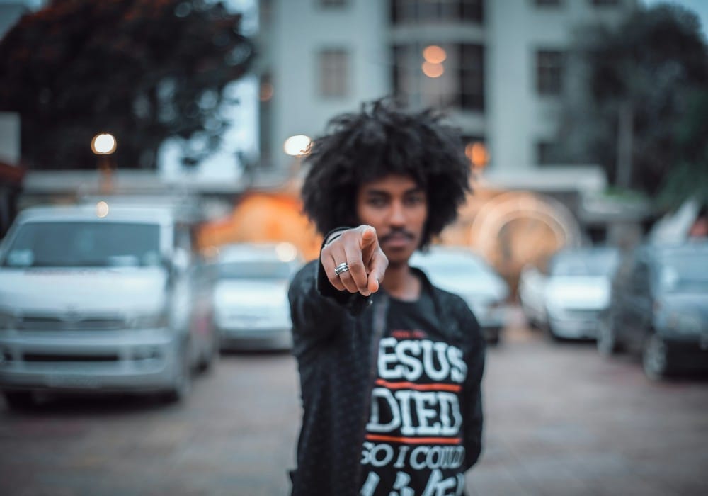 Black man with afro pointing at the camera in urban setting