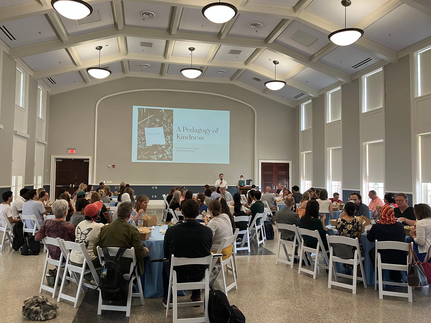 photo of a ballroom with tables full of UM faculty and a slide projected at the front that reads "A Pedagogy of Kindness"