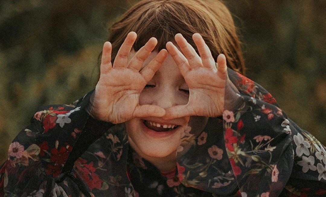 woman in black red and green floral long sleeve shirt covering her face