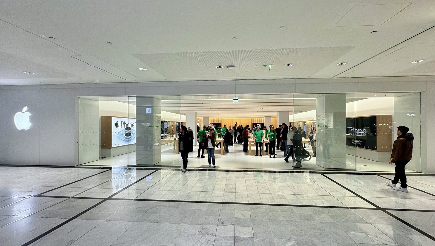The facade of Apple Parly 2 on grand opening day. A backlit Apple logo is set in a quartz panel to the left of the entry.