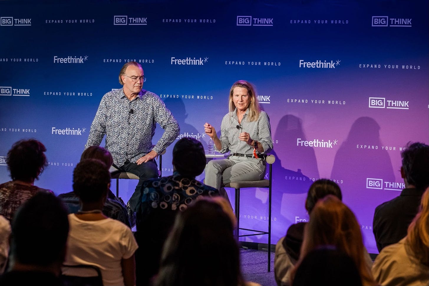 Two speakers sit on stage in front of a seated audience, engaging in a discussion at a Freethink and Big Think event. Two speakers sit on stage in front of a seated audience, engaging in a discussion at a Freethink and Big Think event.