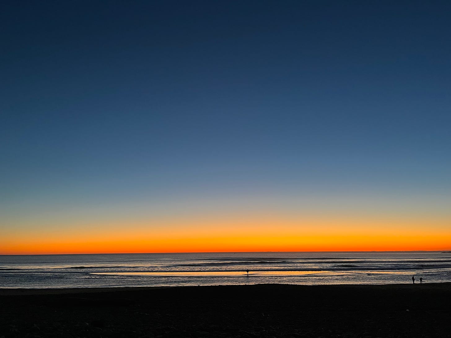 Dark blue sky with dark orange band on the horizon, from the beach.