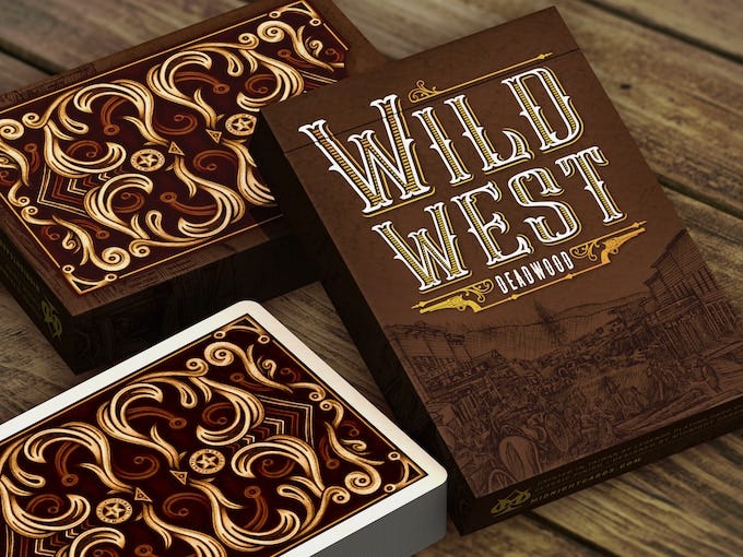 Two decks of Wild West-themed playing cards next to a tuck box.