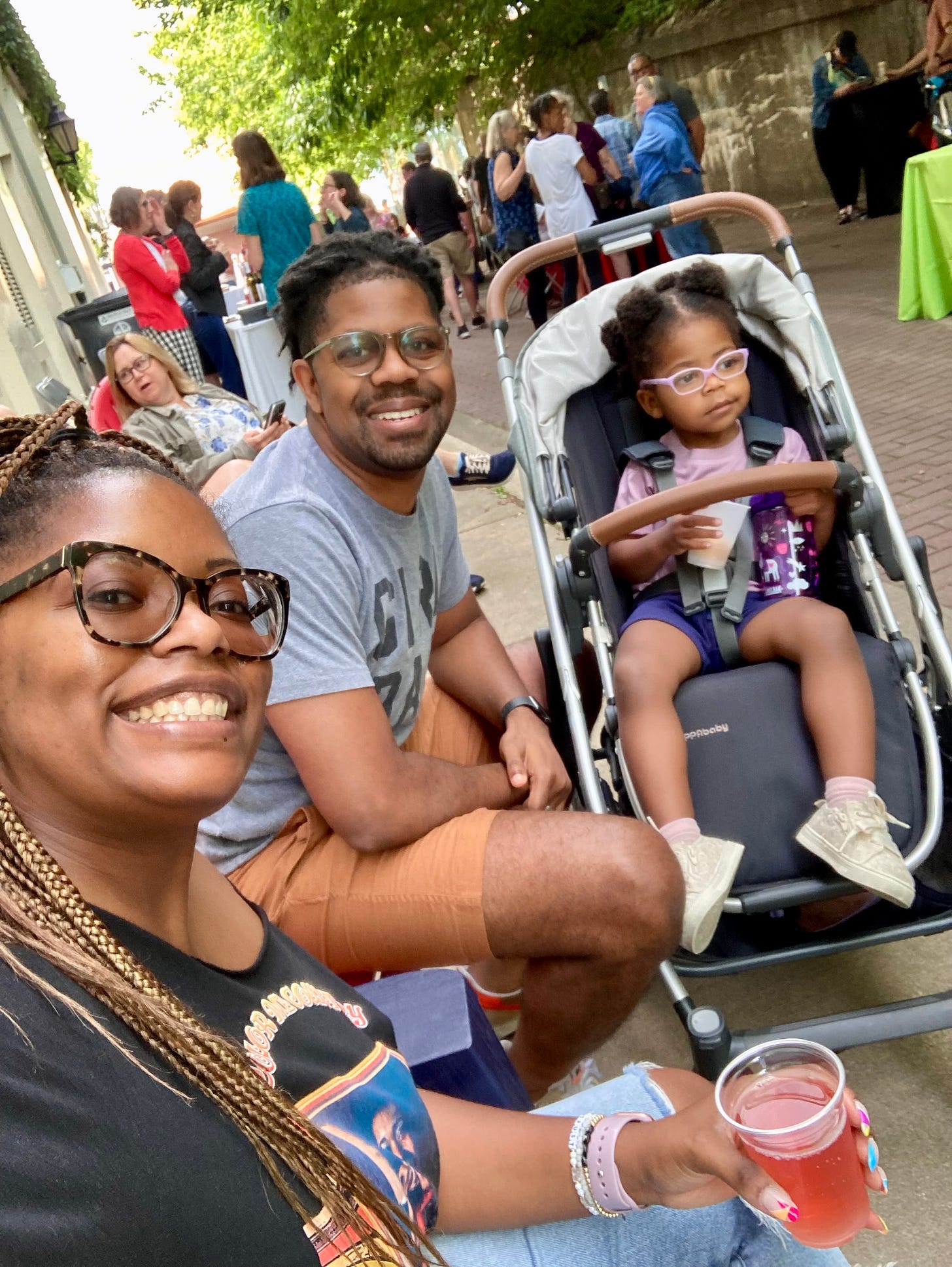Picture of a Black mom, dad and toddler girl at a summer festival