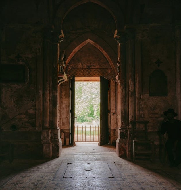 A dark hallway with an open door leading to another room A dark hallway with an open door leading to another room
