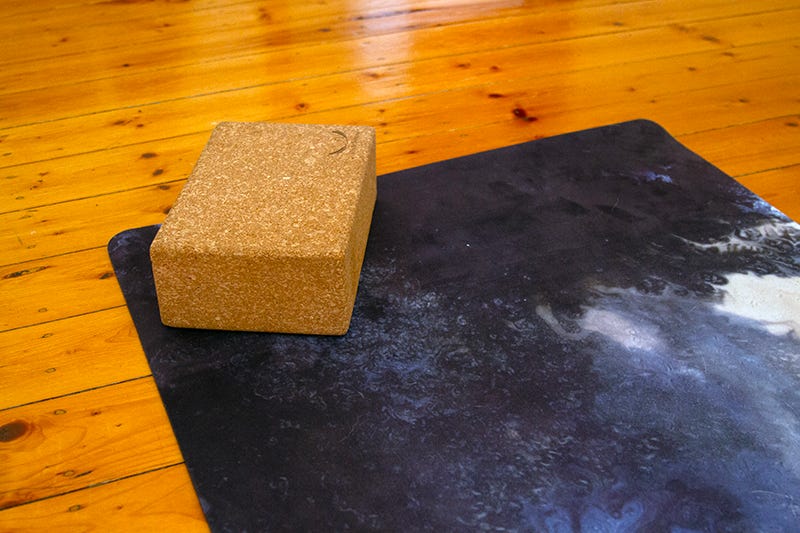 Stormy pattern yoga mat and cork block on a wooden floor.