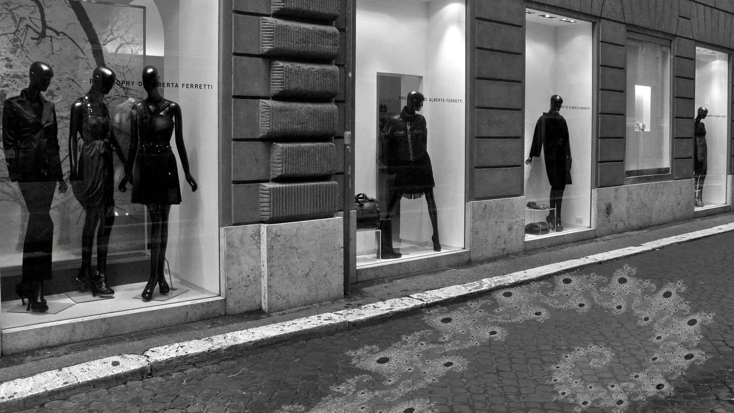 A photo of mannequins in display windows along a street. A portion of the Mandelbrot set is superimposed upon the road.