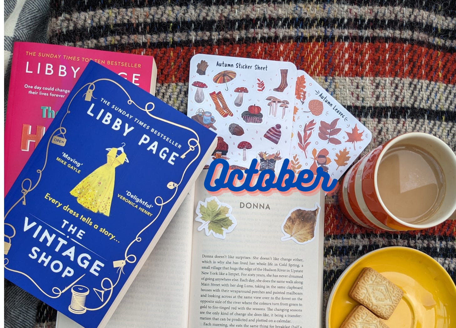 A pile of books including The Vintage Shop, on an autumnal blanket with a cup of tea, biscuits and some autumnal stickers.