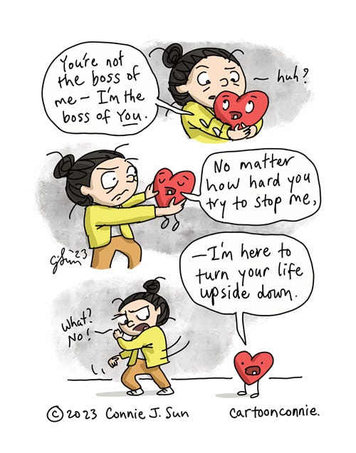 The Boss Of You 3-panel borderless comic of a girl with a bun, holding a plushy cartoon in her arms, titled "The Boss Of You." Panel 1: Plushy heart looks up at girl and says cheerfully, "You're not the boss of me - I'm the boss of you." Girl looks quizzical: "Huh?" Panel 2: Girl holds the heart at arms length now and Heart goes on to say, "No matter how hard you try to stop me..." Panel 3: Heart continues, "-- I'm here to turn your life upside down." Girl drops the heart and recoils in apprehension: "What? No!" Part 10 of a series of plushy heart comics, by Connie Sun, cartoonconnie, 2023.