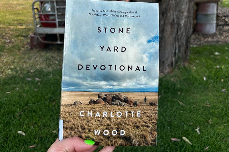 Hand holds a copy of 'Stone Yard Devotional' by Charlotte Wood.