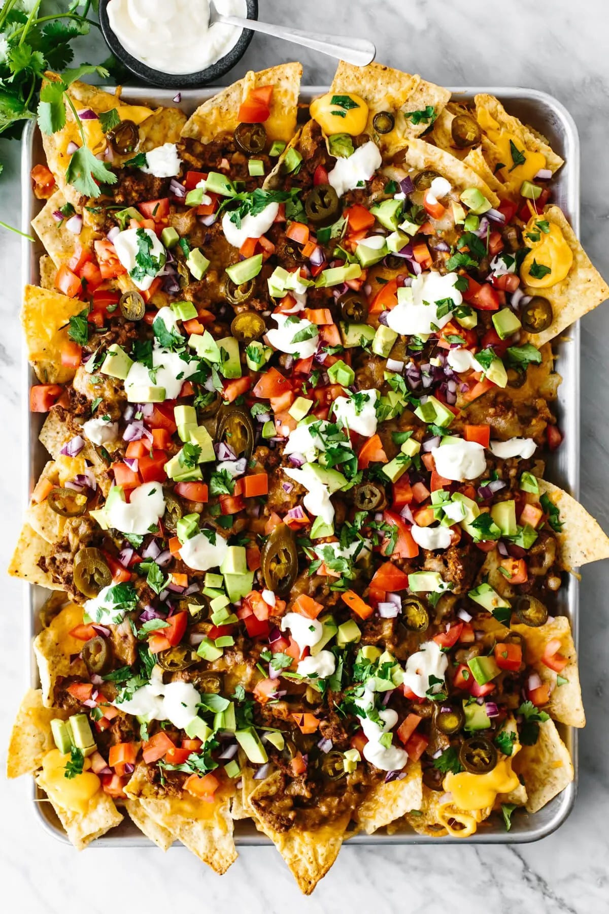 A massive tray of loaded nachos with sour cream on top.